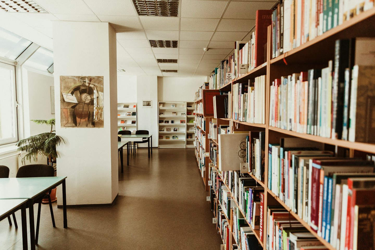 Leerer Lesesaal einer Bibliothek mit Bücherregalen und Tischen.
